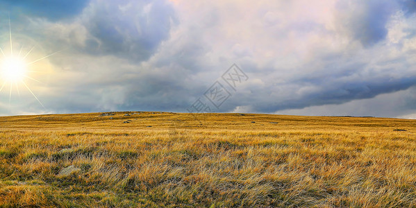 夏日草甸景观与阳光和戏剧暴风雨云景图片
