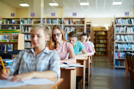 Pensive学生和她的大学同校准备在图书馆举办图片