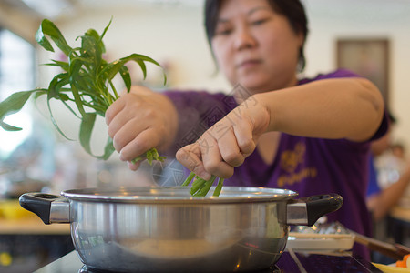 亚洲女通过将蔬菜晨光放到热锅里做一个苏kiyaki或shab图片