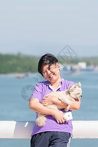 亚洲女人丰满的身体和她的狗在旅行时站在河口图片