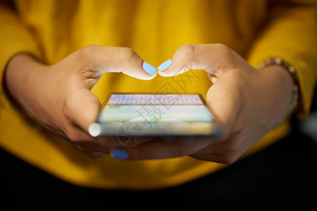 年轻女使用手机在夜间社交网络上发送短信用背景电脑笔记本电脑亲近手接图片