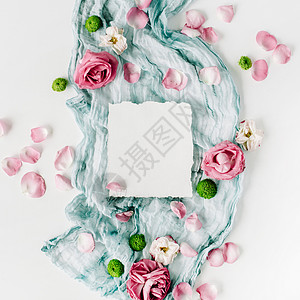 白色背景上的红玫瑰粉红色花瓣和蓝色纺织品图片