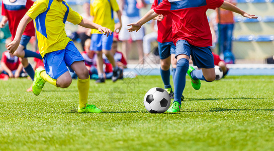 青少年足球比赛孩子们在运动场上踢足球男孩在球场上踢足球比赛图片