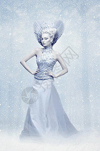 打扮成冬皇后的年轻美女的肖像创意化的妆品在雪地背景图片