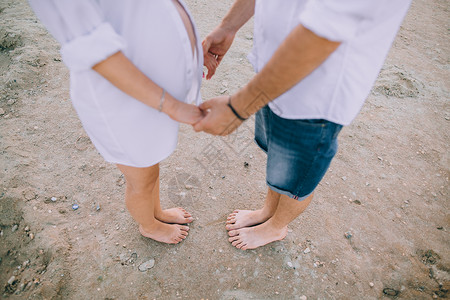 牵手走在沙滩上的怀孕夫妇图片