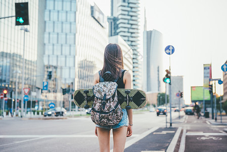 在城市户外的年轻美丽无异女背着包和滑溜冰旅行者图片