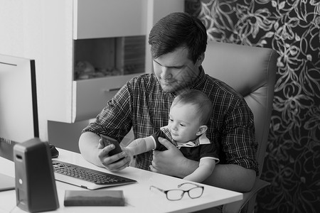 年轻人在家工作和照顾婴儿的黑白肖像图片