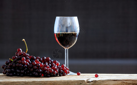 木桌上的红葡萄和一杯酒图片