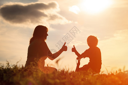 快乐的母亲和儿子在日落天空骑图片