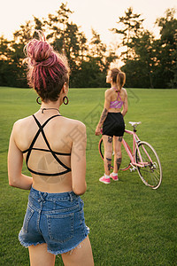 和骑自行车的最好的女朋友一起玩得开心在日落时看着她们面前的女孩们图片