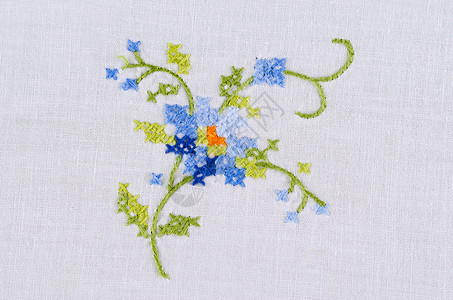 白麻布桌上的蓝色花纹手刺绣背景图片