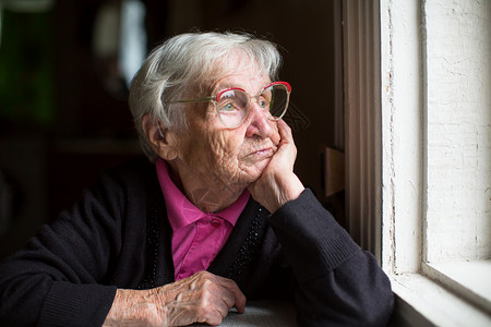 戴眼镜的老妇人若有所思地望着窗外图片