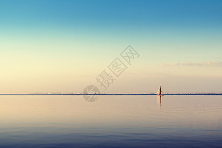 白帆船在日落的宁静水面上漂浮着海景并收图片