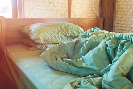 绿色枕头和毯子在旧木制卧室的床上布满皱纹乱七八糟图片
