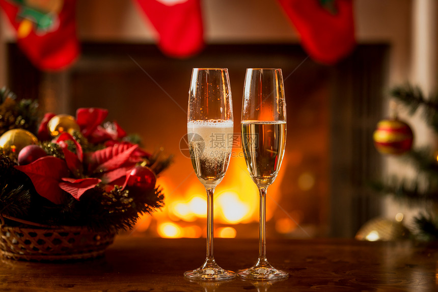 两杯香槟在燃烧的壁炉前的特写镜头图片