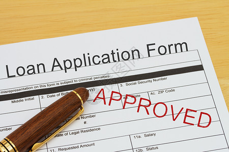 用笔在桌子上申请贷款批准的贷款申请表图片