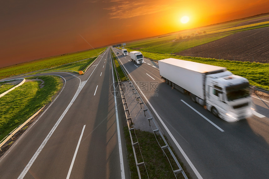 许多白色卡车驶向太阳在美丽的日落高速公路上的快速模糊图像塞尔维亚贝尔格莱德附近高速公路图片