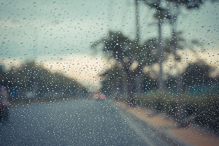 汽车挡风玻璃和雨滴在路面背景下以图片