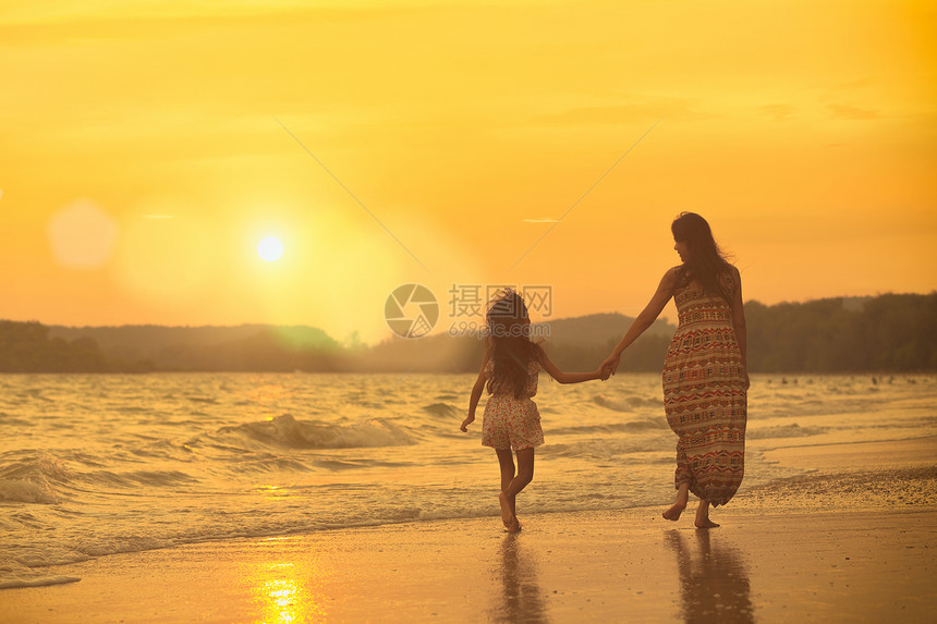 母女俩在夕阳西下的沙滩上散步图片