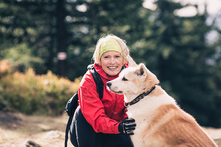 与秋田犬在森林小径上徒步旅行的女人图片