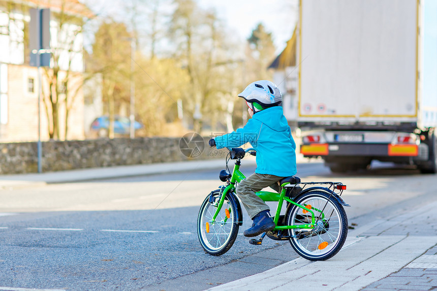 学龄前儿童男孩骑自行车在城市的道路上儿童汽车和轨图片