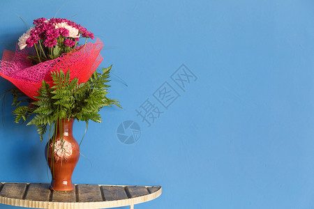 蓝色木墙背景桌子上蓝色花瓶中的花束照片图片