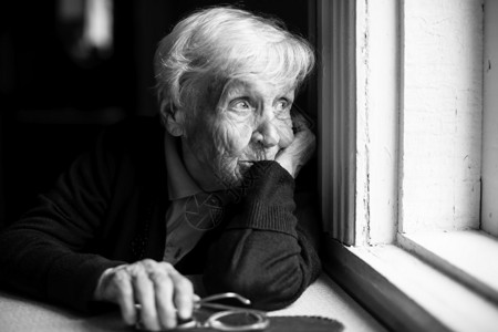 悲哀的老年妇女向窗外图片
