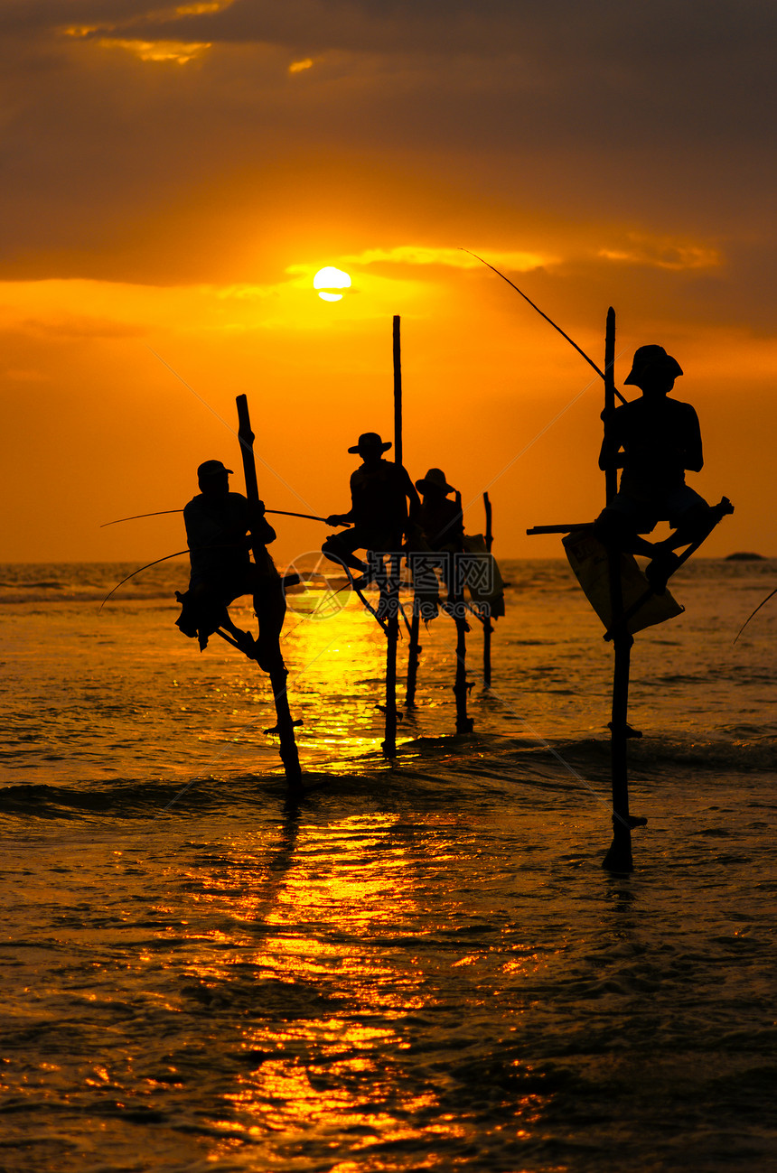 日落时传统高跷渔民的剪影图片