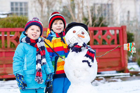 两个小兄弟姐妹孩子们在寒冷的日子里在户外堆雪人玩耍和玩雪冬季与孩子图片