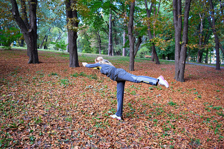 那个女孩在秋天的公园里练瑜伽图片
