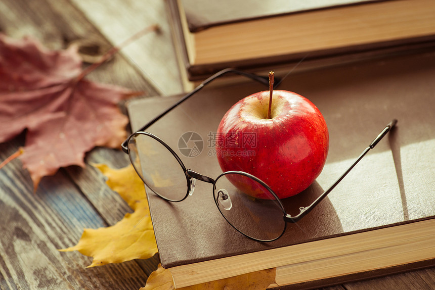 木桌上有书和秋叶的眼镜图片