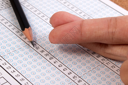 在测试概念中作弊在多项选择答题纸上作弊的手指交叉学生考试作弊学校考试答题纸和铅笔答案纸集中在背景图片