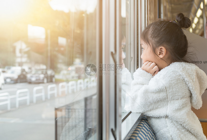 可爱的小女孩透过窗户看着她坐火车旅行图片