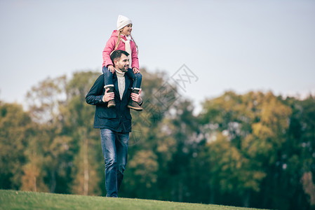 在秋季公园散步时微笑的父亲肩上扛着图片