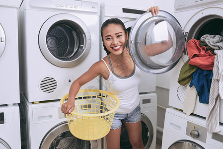 可爱的年轻女子从洗衣机中洗图片