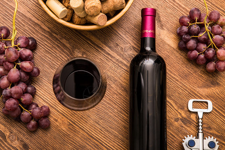 木制背景上的酒瓶酒杯葡萄和软木酒图片