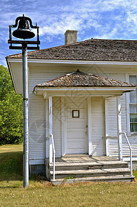 一个铃铛位于一所旧单间校舍的入口前图片