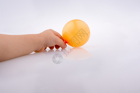手拿着一个白色背景上的彩色小气球背景图片