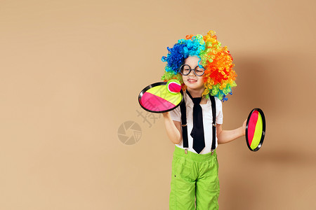快乐的孩子们戴着大霓虹色假发的快乐小丑男孩的画像戴着小丑假发和眼镜的孩背景图片