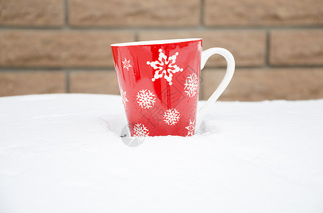 冬天的雪天在篱笆的背景下一杯红色的图片