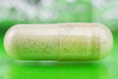 Glucosamine胶囊以光彩绿色背景为食用补充药片宏观图像软模图片