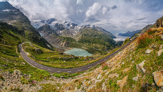 摩托车手在阿尔卑斯山蜿蜒的山口公路上行驶图片