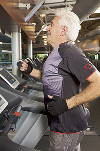 老人在健身房的跑步机上锻炼图片