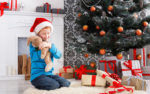 戴着圣诞帽的可爱快乐男孩拥抱玩具兔子图片