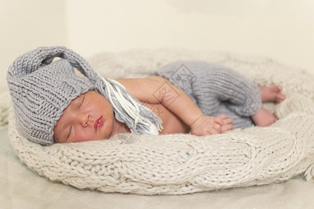睡在包裹里的新生婴儿穿灰色西装给婴儿织毛衣图片