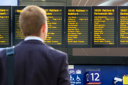 在火车站检查时间表的通勤者图片