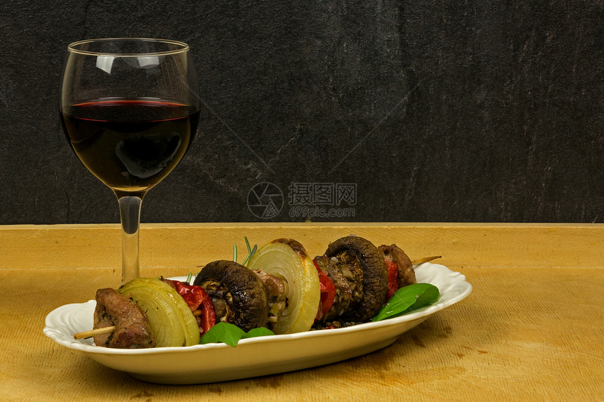 白色盘子上的牛肉小菜和红葡萄酒的滑板图片