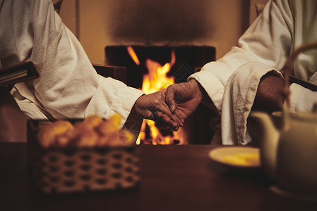 情侣在壁炉边放松时手牵背景图片