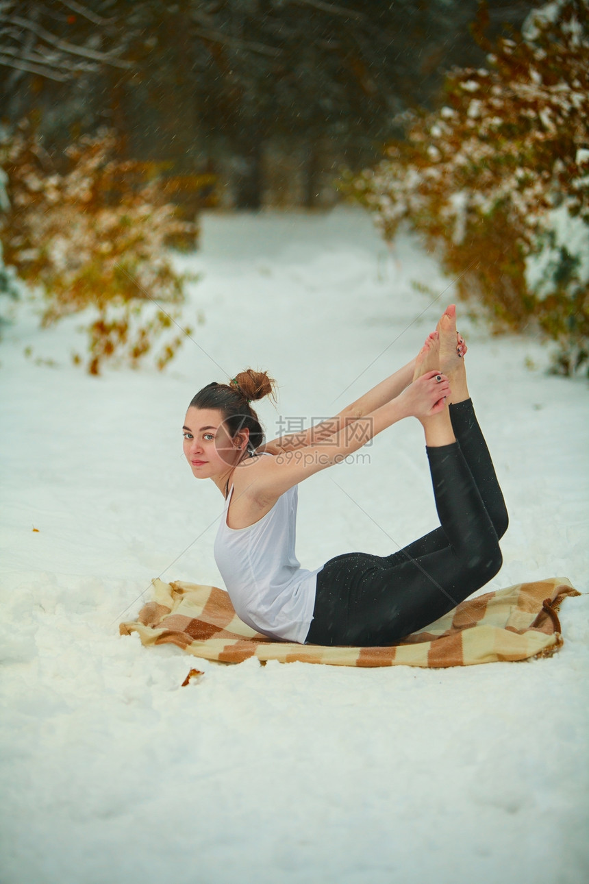 美丽的女人在雪地里做户外瑜伽图片