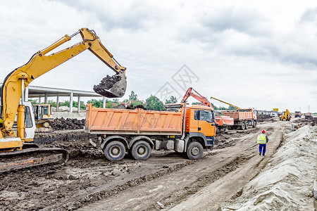 黄色挖掘机正在施工地用土填充倾卸卡车项图片